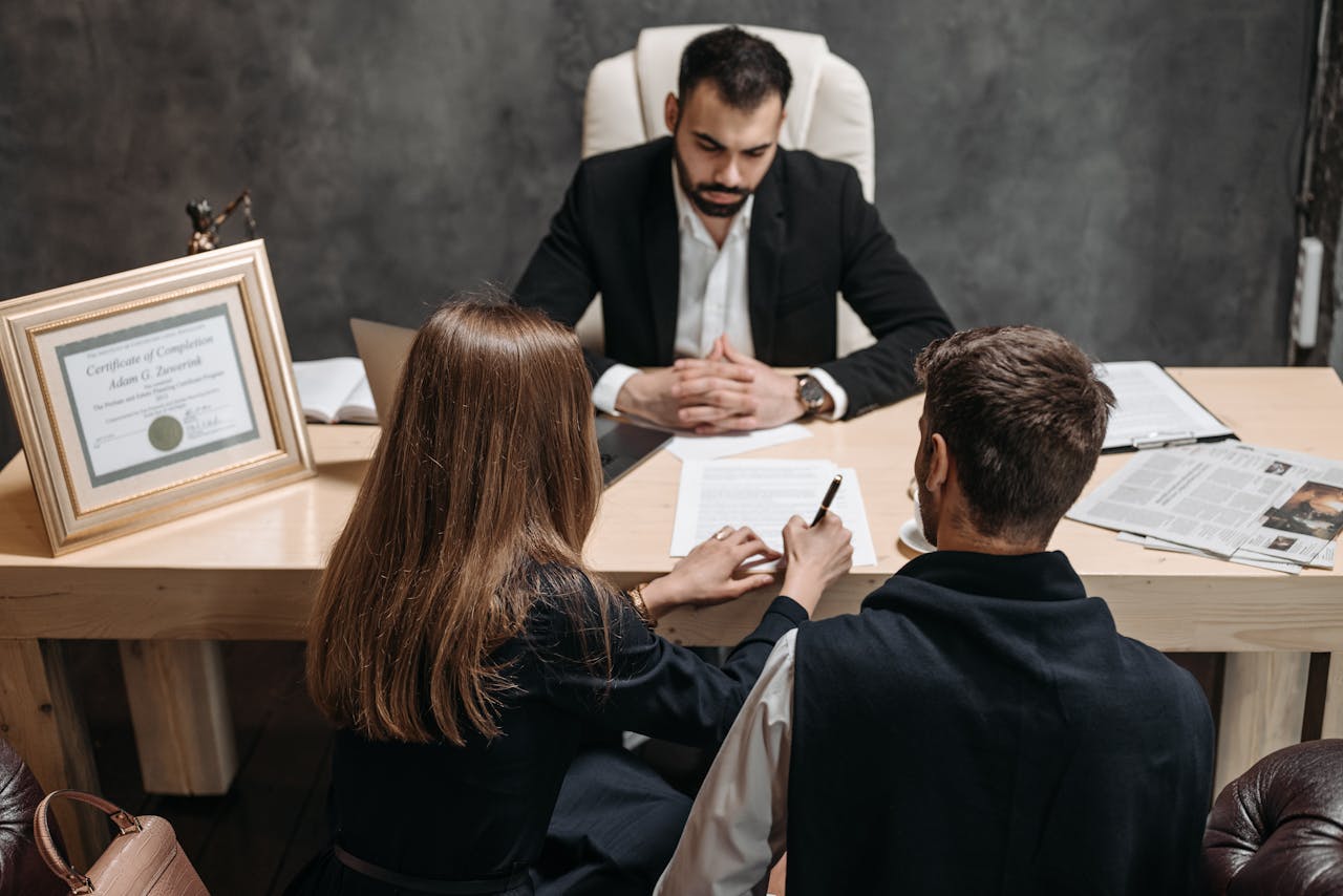 services-04 A lawyer discusses legal documents with clients in an office setting.